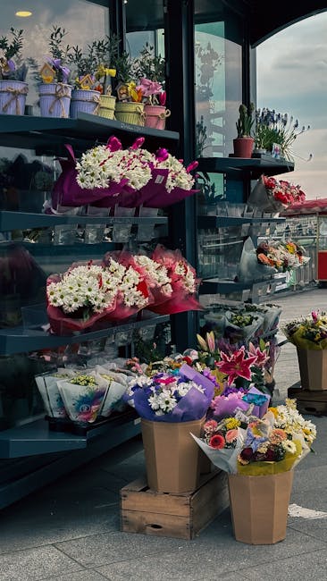 A display of various floral arrangements at a flower shop near West Brompton station. On the top shelf, small potted plants and bouquets wrapped in pastel-colored paper sit in decorative pots and wrap