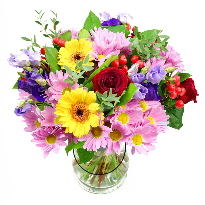 A lush, full bouquet of mixed seasonal flowers stands proudly in a clear glass vase, its silhouette rounded but slightly relaxed, as though freshly arranged on a Brompton kitchen table. At the core, rich red roses form velvety cups of colour, their petals tightly layered and gently curved, adding a sense of depth and quiet sentiment to the design. Two golden-yellow gerbera daisies rise beside them, their wide petals radiating around dark brown-orange centres, like little sunbursts that bring immediate cheer to the composition. Encircling this central group, clusters of pale to mid-pink daisies or chrysanthemums spill outward in soft waves, their many fine petals and tiny yellow centres creating a calm, reassuring backdrop that softens the stronger tones. Slender stems of lisianthus in shades of purple and lavender thread delicately among the other blooms, some buds still half-closed, contributing an elegant, bell-shaped contrast and a cooler, refined note reminiscent of a peaceful walk through nearby Brompton Cemetery's tree-lined paths. Bright red hypericum berries, glossy and round, peek from between the petals like small jewels, lending an unexpected texture that catches the light. Layers of mixed greenery-broad deep-green leaves, lighter fresh shoots, and finer airy foliage-support and frame the flowers, filling any gaps so the arrangement looks generous from every angle. The straight, trimmed stems are clearly visible through the transparent vase, submerged in clean water that hints at just-cut freshness. Even, clear lighting enhances the colours and shows subtle shadows between petals and leaves, giving the bouquet a three-dimensional, almost touchable quality. This arrangement feels joyful yet composed, ideal for birthdays, anniversaries, or a thoughtful delivery to brighten a Brompton flat overlooking the quiet streets near Thurloe Square.