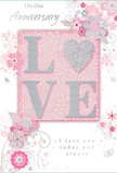 An exquisite anniversary card is displayed as though waiting beside a freshly delivered bouquet in a Brompton home, its design radiating gentle romance. The word LOVE forms the main feature, rising from the card in softly sculpted, glitter-dusted letters that invite touch; the sparkle is subtle, more like a soft shimmer than a bold shine, and carries hints of silver that glint when viewed from different angles. This tactile word rests on a blush-pink panel with tender gradations of tone, which in turn sits against an ethereal backdrop of pearlescent white and hinting grey, giving the card a light, dreamy atmosphere. Flowing around the central motif, an intricate pattern of stylised flowers and trailing leaves unfurls, their fine lines and delicate shading recalling the careful outlines a florist might make before arranging real stems in a vase. The blooms and foliage sway across the surface in blush, powder pink, muted mauve, and soft silver, forming graceful arches and curls that frame the raised text. Between these decorative sweeps, a refined script spells out anniversary wishes and notes of enduring love, the typography elegant yet understated. Negative space is used thoughtfully, allowing each swirl and petal to breathe and ensuring the design never feels cluttered. The overall impression is of a card that captures the feeling of an intimate celebration-like an evening spent near the quiet mews off Brompton Road-serene, heartfelt, and beautifully composed, a paper echo of a softly fragrant anniversary bouquet.